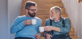 Adult child smiling at dad over coffee cup